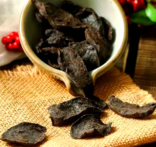 资深酿酒师展示正在浸泡中的枸杞何首乌养生酒，酒体金黄透亮，药材清晰可见。_1