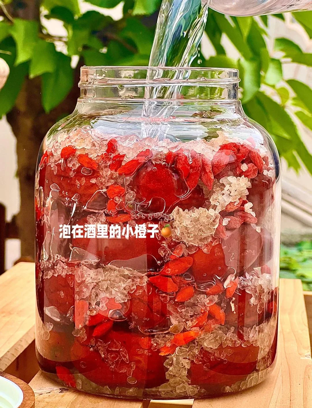 家庭自制的红枣枸杞泡酒，装在透明玻璃罐中，色泽琥珀，红枣与枸杞清晰可见，摆放于木桌之上，体现安全与温馨。_1