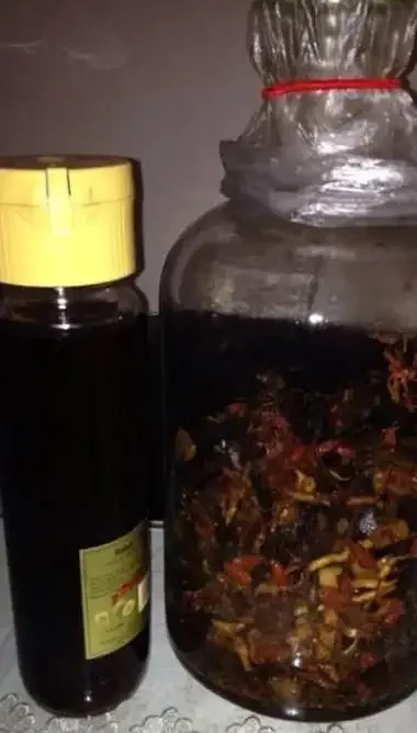 一个装有中药材的透明玻璃泡酒罐，旁边有一瓶酱香型白酒，展示了泡制药酒的过程。_1