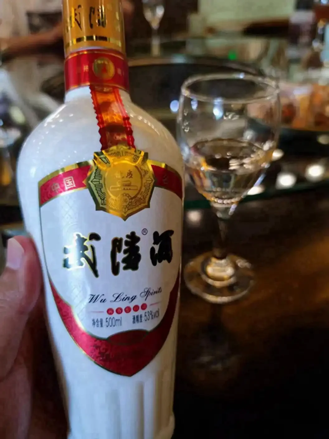 酿酒老师傅在酒厂储藏间展示一杯清澈的白酒_1