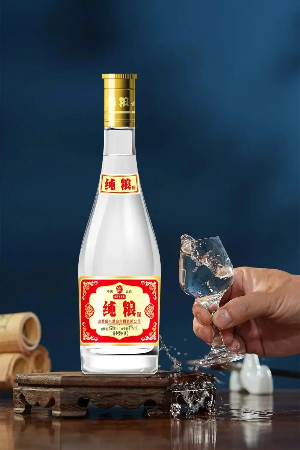 一只手在家庭餐桌前举起一杯清澈微黄的纯粮食酒，杯壁有明显的挂杯现象。_1