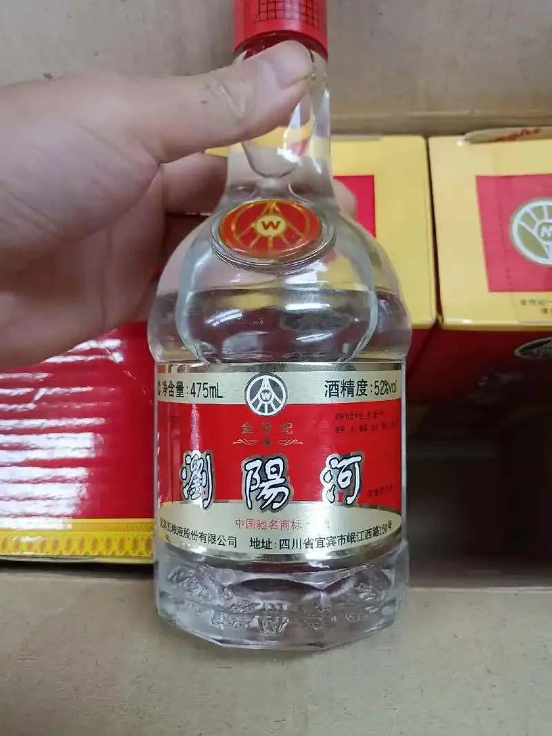一瓶52度白酒放置在木质酒柜前的桌面上，周围散落着酿酒原料，展示白酒的陈年与专业储存环境_1
