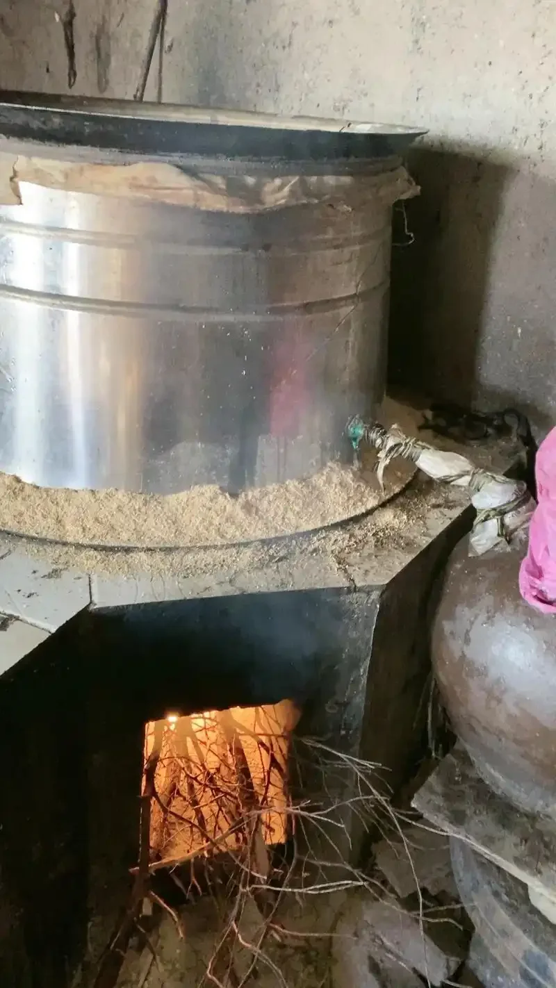 资深酿酒师在传统酒坊中操作泸州生产的现代化不锈钢烤酒设备_1