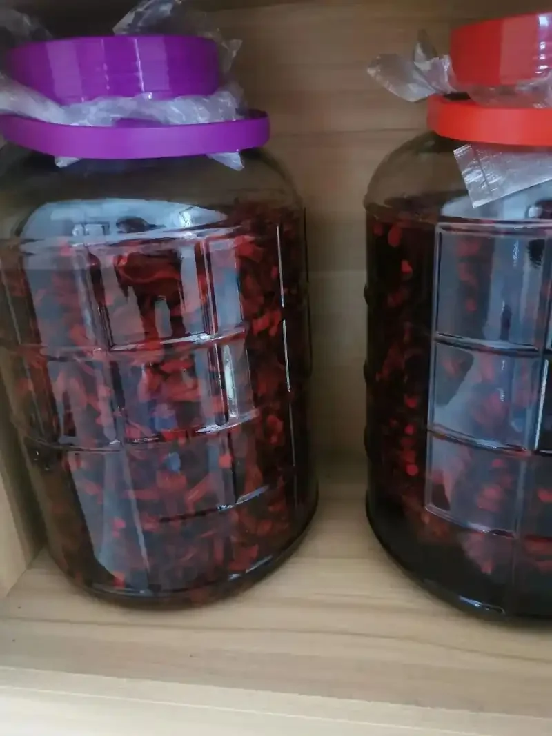 红桃K泡酒制作过程：装满红桃K花瓣和白酒的透明玻璃罐，旁边散落着原材料。_1