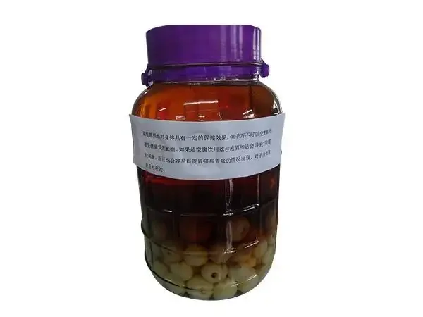 家庭自酿的琥珀色龙眼酒在玻璃罐中，旁边是新鲜龙眼，展现传统果酒的温润质感。_1