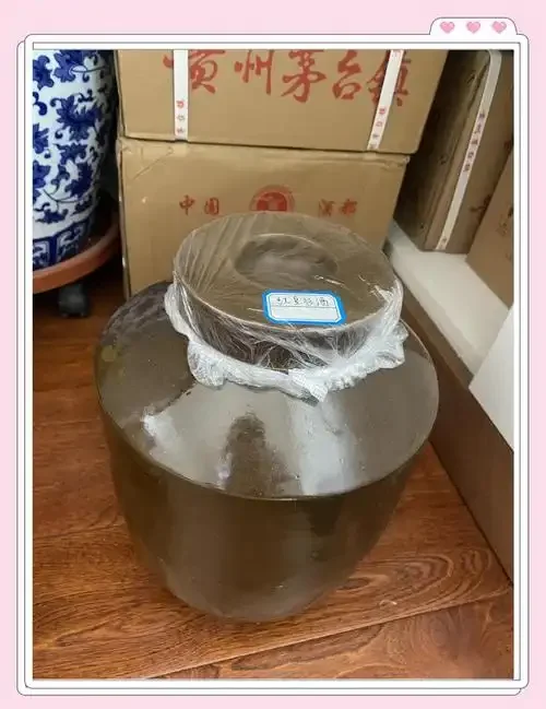 一个密封良好的玻璃酒坛，坛口用布、保鲜膜和绳子多层封扎，展示家庭自酿粮食酒的正确密封方法。_1