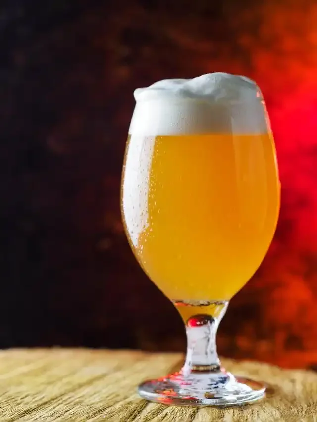 专业酿酒师正在进行精酿啤酒的糖化步骤，糖化桶内麦汁色泽金黄，背景有麦芽和工具。_1