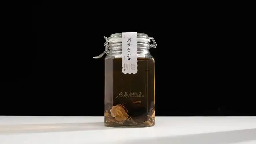 家庭自制枸杞玛卡泡酒：透明玻璃罐中琥珀色酒液浸泡着红色枸杞和黄色玛卡片_1