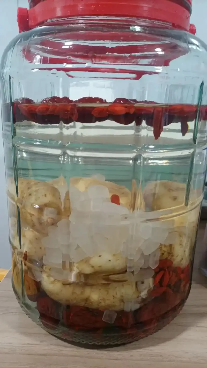 家庭自制天麻泡酒的微距特写，展示清澈酒体与药材，以及背景中的天麻干和称量工具，体现安全与专业。_1