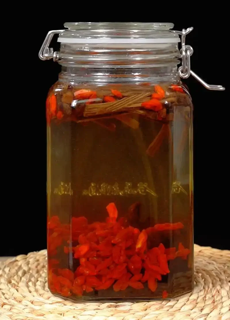 蛤蚧、鹿鞭切片、枸杞、白酒和玻璃罐等泡酒材料准备齐全的俯拍桌面展示_1