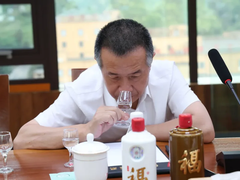 酿酒师在工作室品酒，背景可见贵州酿酒工业协会会员单位铜牌_1