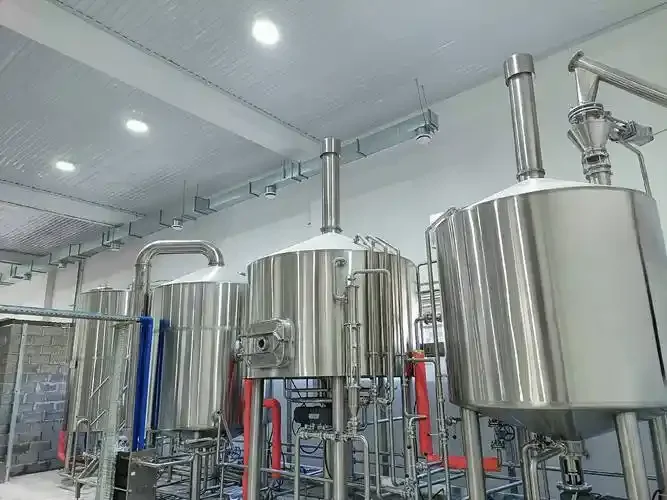 一名酿酒师在精酿啤酒工坊内检查不锈钢酿造设备的特写照片_1