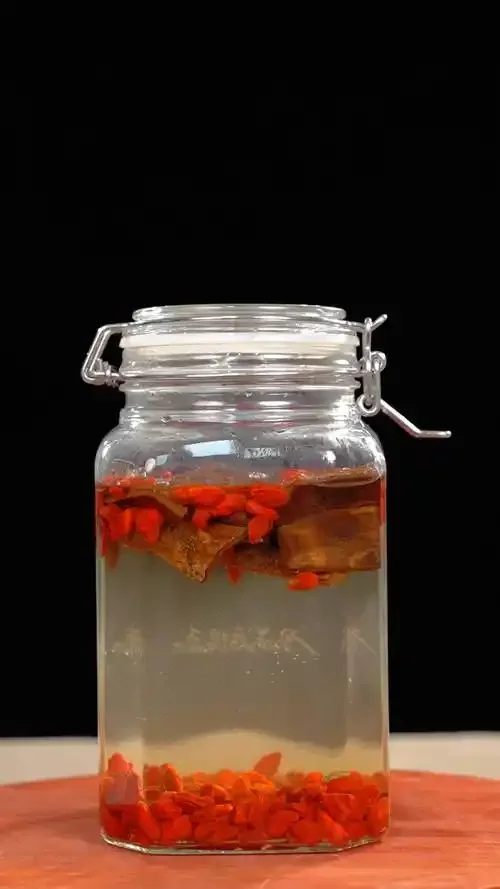 泡药酒选酒指南：透明玻璃酒坛内浸泡着多种中药材，旁边摆放着不同香型白酒瓶，展示如何选择泡药酒基酒。_1