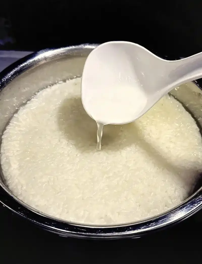 家庭自制米酒发酵过程实拍图，透明玻璃罐内米饭与清澈酒液清晰可见。_1