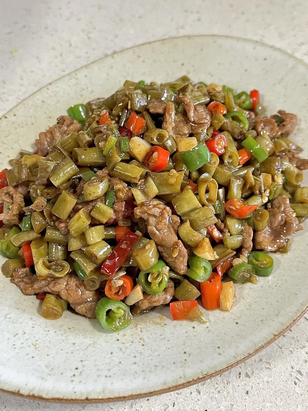 泡菜坛中正在发酵的酸豆角，旁边放着一小瓶白酒、大蒜和生姜，展示家庭制作酸豆角的场景。_1