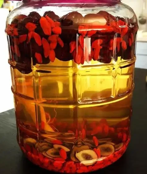 透明玻璃泡酒罐中，人参和鹿茸浸泡在琥珀色酒液里，展示家庭泡制药酒的专业方法_1