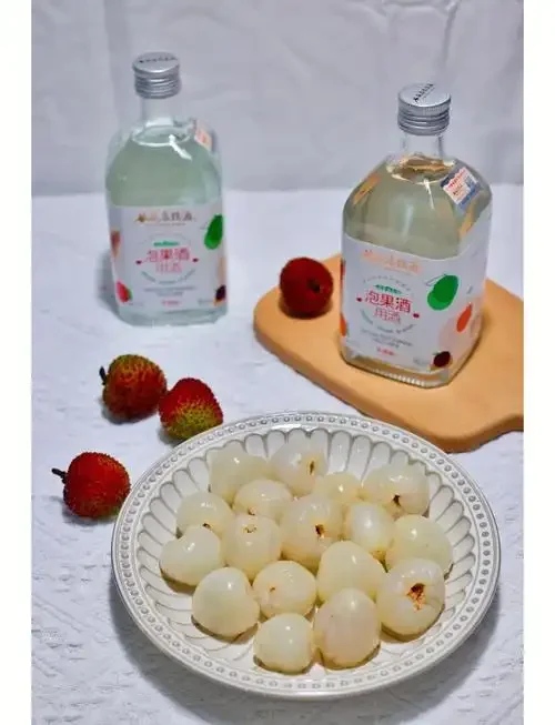 家庭自制荔枝泡酒的特写照片，展示玻璃罐中饱满的荔枝果肉与琥珀色酒液_1