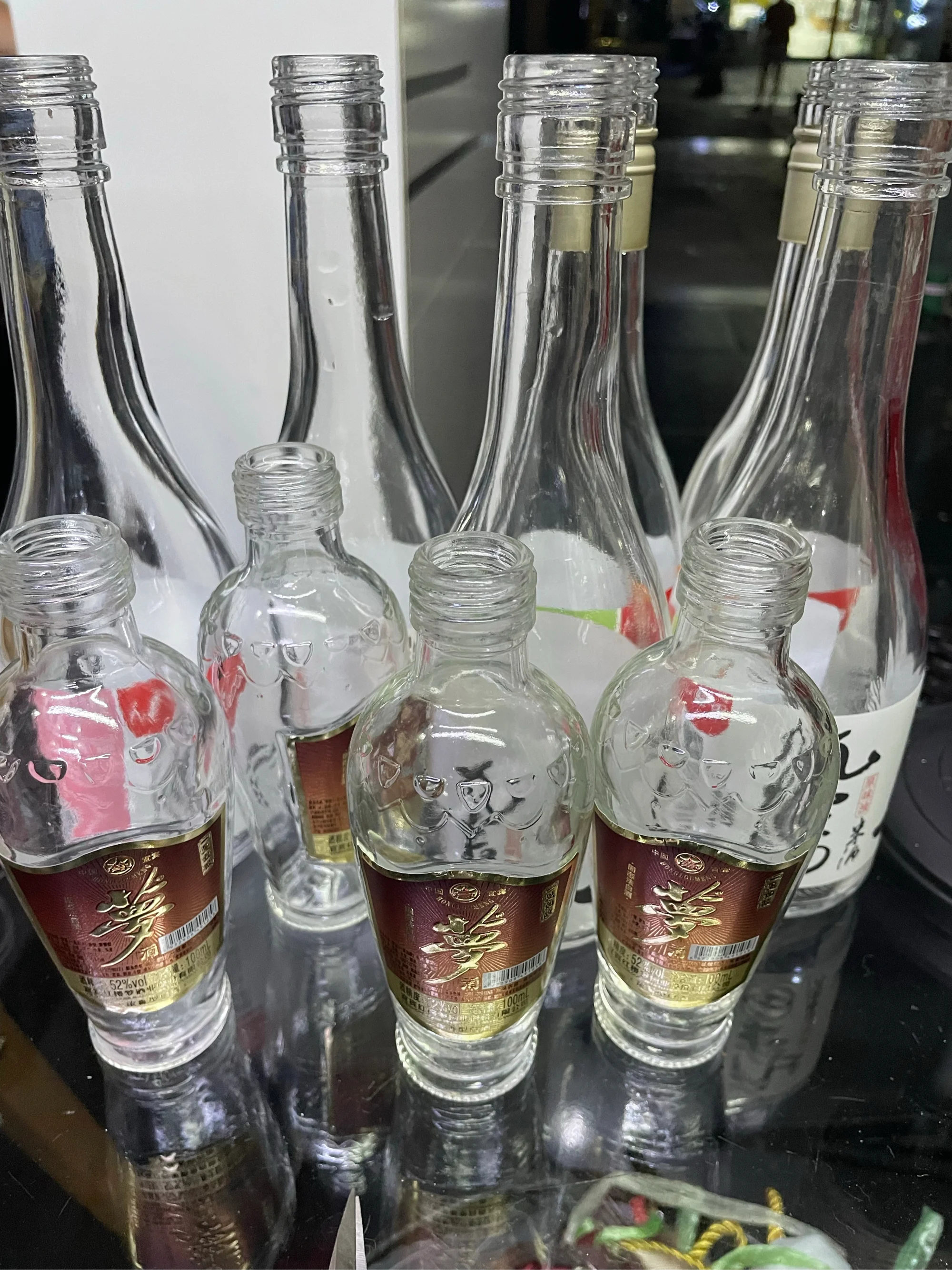 清洗干净的白酒空瓶插着干花，摆放在酿酒师的工作台上，旁边有酿酒工具，展现空酒瓶的创意再利用。_1