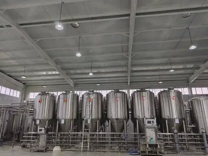 山东啤酒设备制造车间内景，展示不锈钢糖化锅、发酵罐及专业师傅检修场景_1