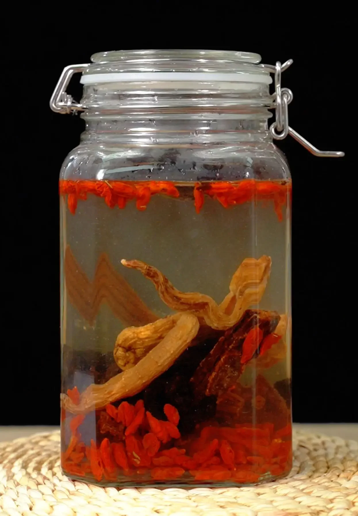 杜仲天麻枸杞泡酒成品展示图：玻璃罐中酒液金黄，药材清晰可见。_1