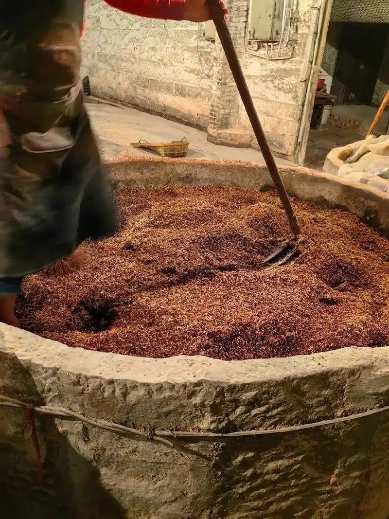 酿酒师用手拨弄刚蒸好的红高粱，展示传统高粱酒制作工艺的选粮与蒸煮环节_1