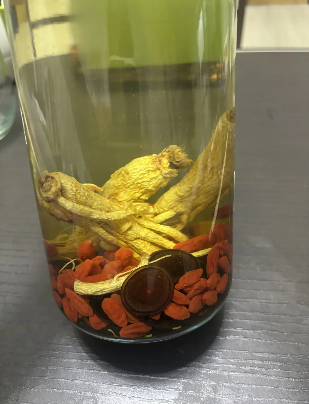 人参鹿茸养生药酒配方示例：玻璃酒坛中浸泡着人参、鹿茸片、枸杞和麦冬等药材。_1