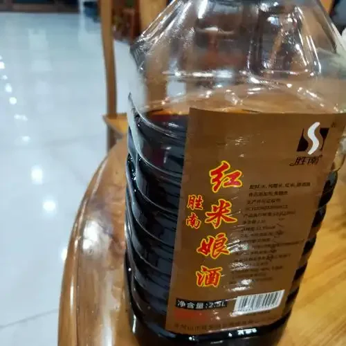正在发酵的红糯米酒醪特写，红糯米颗粒清晰可见，周围摆放着酿酒工具。_1