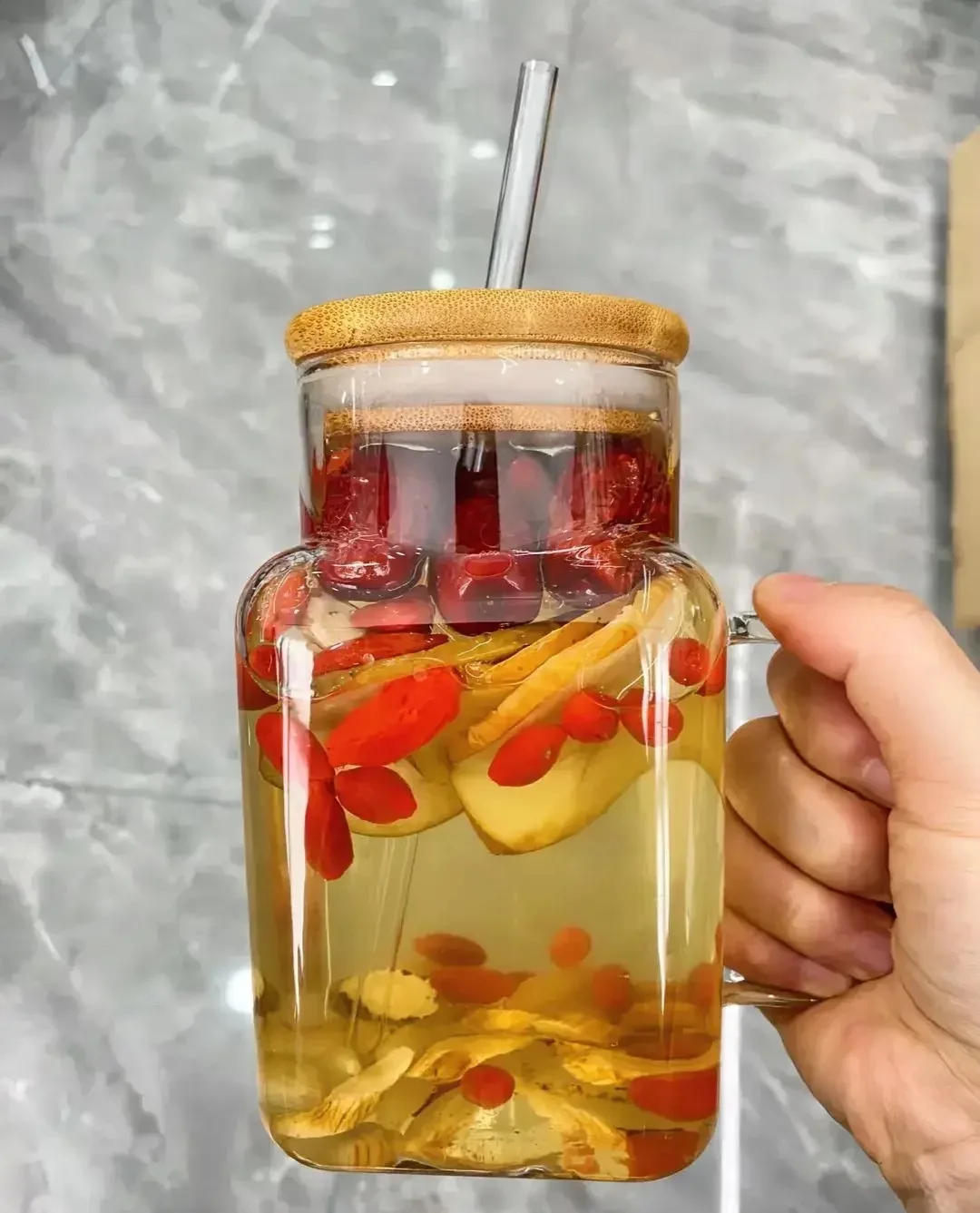 枸杞红枣陈皮山楂家庭泡酒配方实物展示：透明玻璃罐中琥珀色酒液浸泡着红枣、枸杞、陈皮和山楂片_1