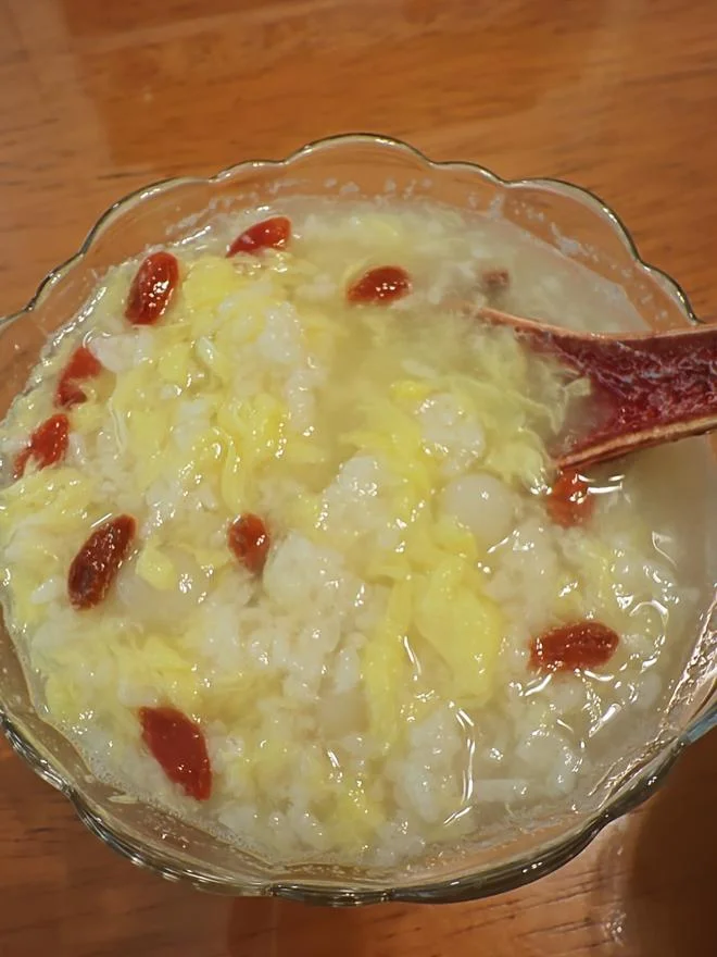 电饭煲内用毛巾包裹着发酵米酒盆，温度计显示30度，展示家庭自制酒酿的保温场景。_1