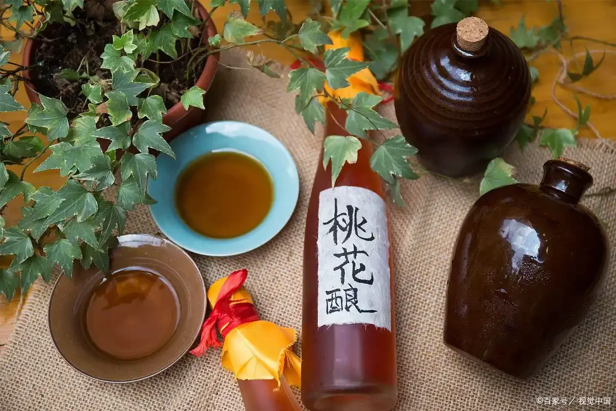 家庭自制桃花泡酒成品展示：淡粉色酒液清澈，瓶中可见完整的桃花瓣与枸杞。_1