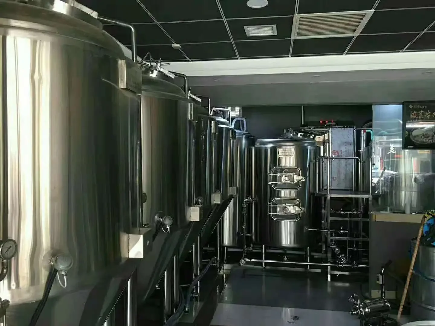 家庭精酿工作室中，一个专业的不锈钢锥形发酵罐，配有温控带和压力表，周围摆放着酿酒工具。_1