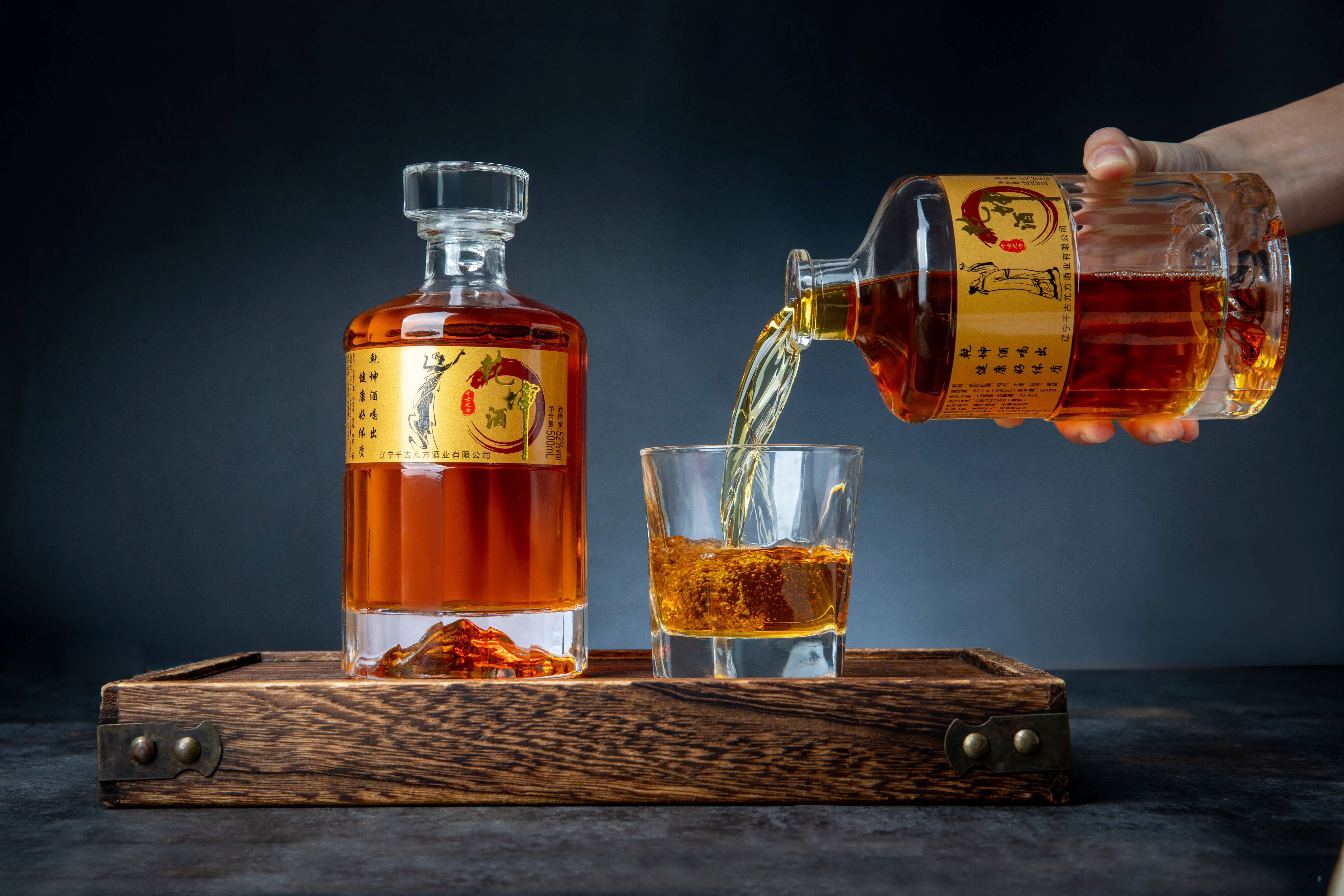 活血化瘀药酒制作过程实拍：透明玻璃罐中浸泡着当归、红花等中药材，旁边散落着药材和配方纸。_1