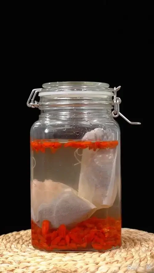 家庭泡养生酒材料实拍：玻璃罐中浸泡着人参、枸杞、红枣的养生酒，旁边散落着待用的精选中药材和黄冰糖。_1