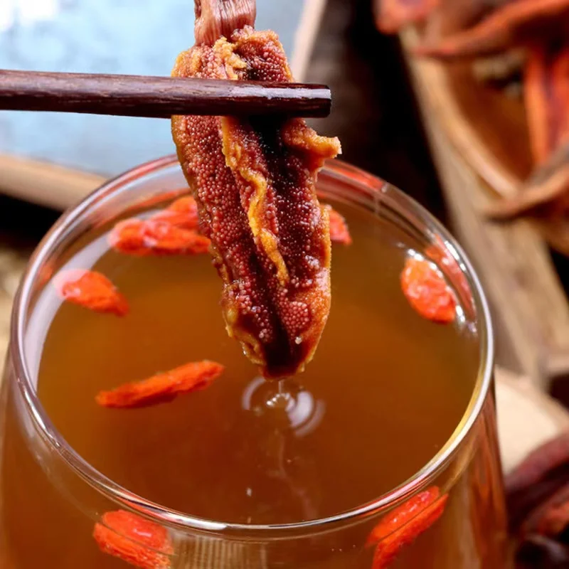 回春草泡酒实物展示：透明玻璃罐中，金黄色的酒液浸泡着回春草、枸杞和人参片，呈现专业家庭泡酒的经典搭配。_1