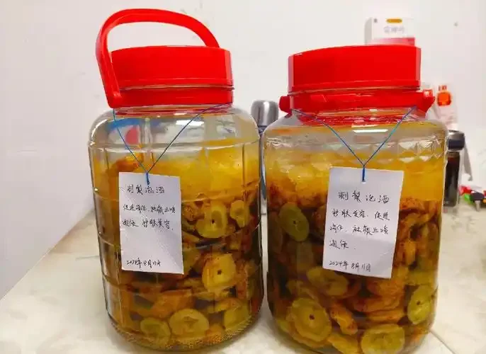 一罐正在浸泡中的金黄刺梨酒，酒液清澈透亮，刺梨果饱满，旁边散落着新鲜刺梨，展现了家庭酿造的温馨与期待。_1