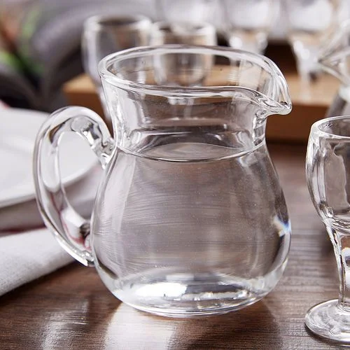 三种不同样式和容量的玻璃分酒器与品酒杯在桌面上的静物组合，展示分酒器的常见规格。_1