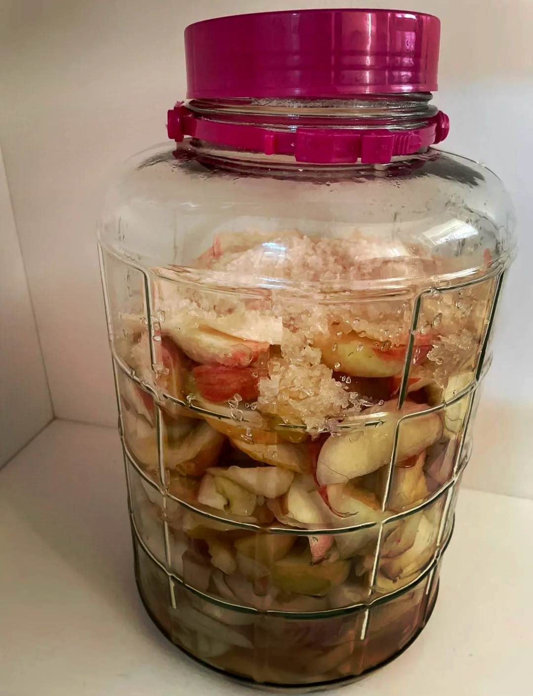 家庭自制果酒特写：玻璃罐中清澈的深红色果酒与新鲜水果、冰糖和酿酒工具摆放在木桌上_1