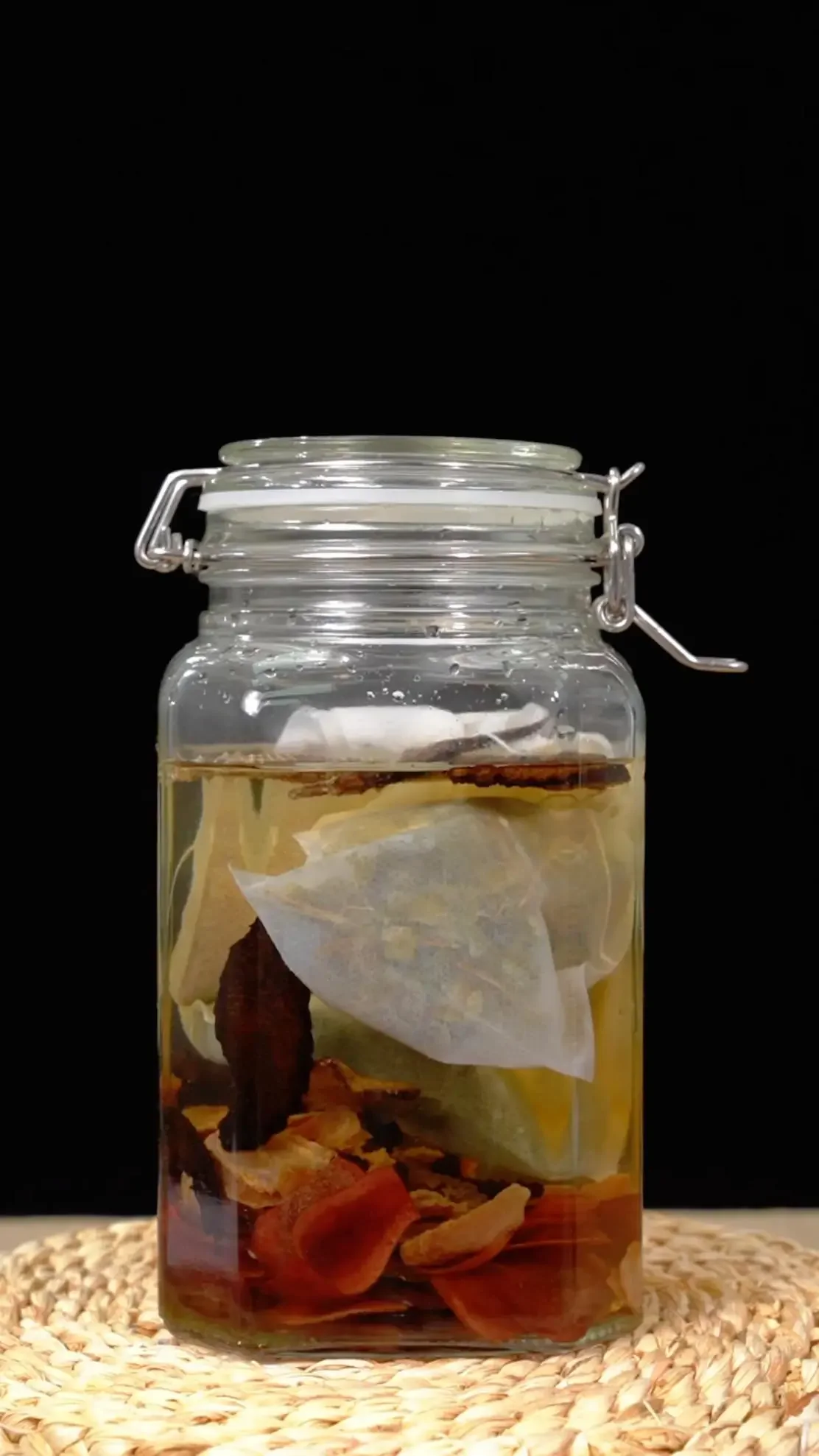 酿酒师在工作室中观察和讲解淫羊藿药酒的浸泡过程，展示了药材与酒液的融合状态。_1