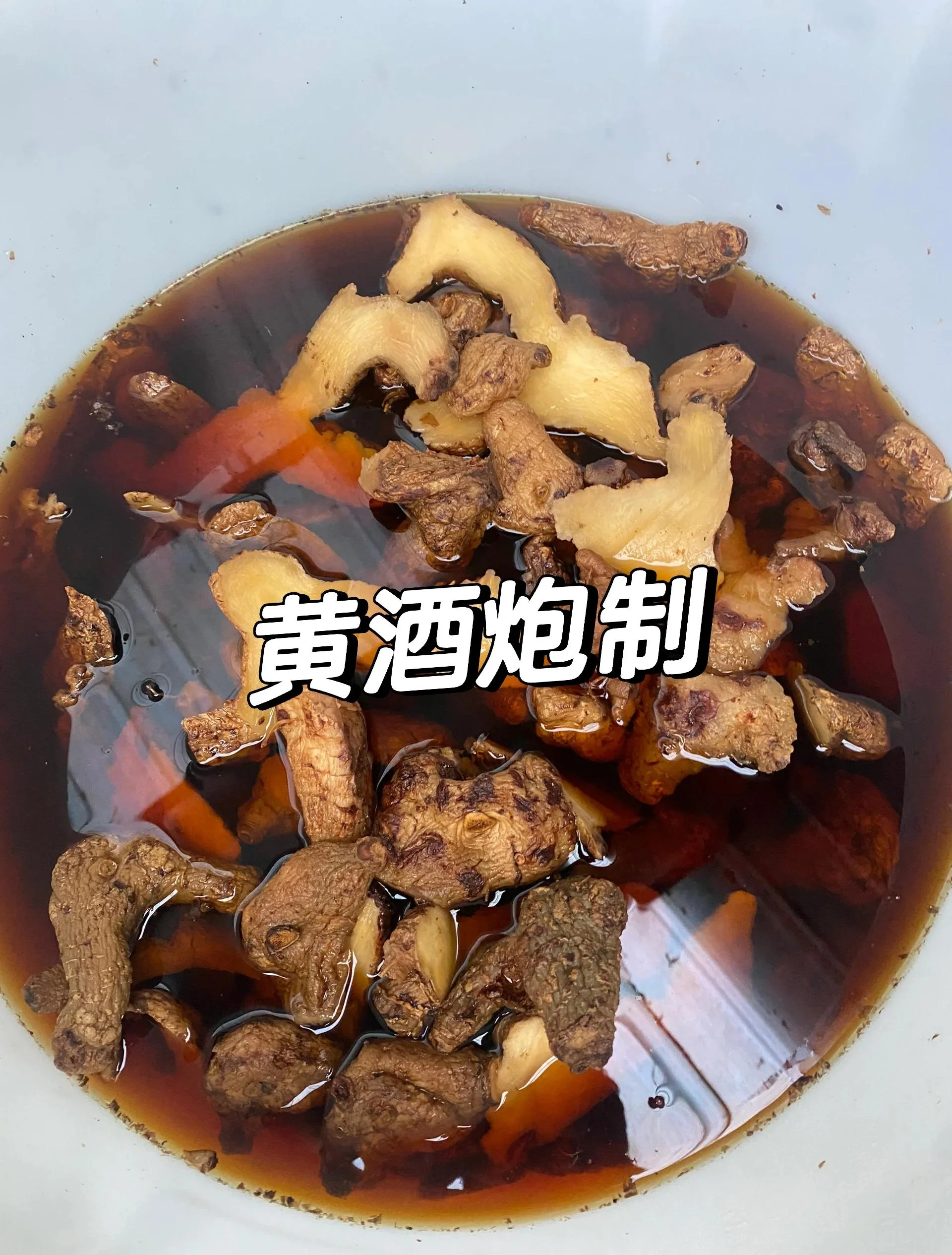 黄精人参泡酒制作过程特写：玻璃罐中呈现金黄色的药酒，旁边是未处理的人参和黄精切片。_1