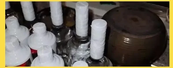 家庭白酒理想存放环境展示：酒柜中玻璃瓶与陶坛白酒，旁边有显示适宜温湿度的温湿度计。_1