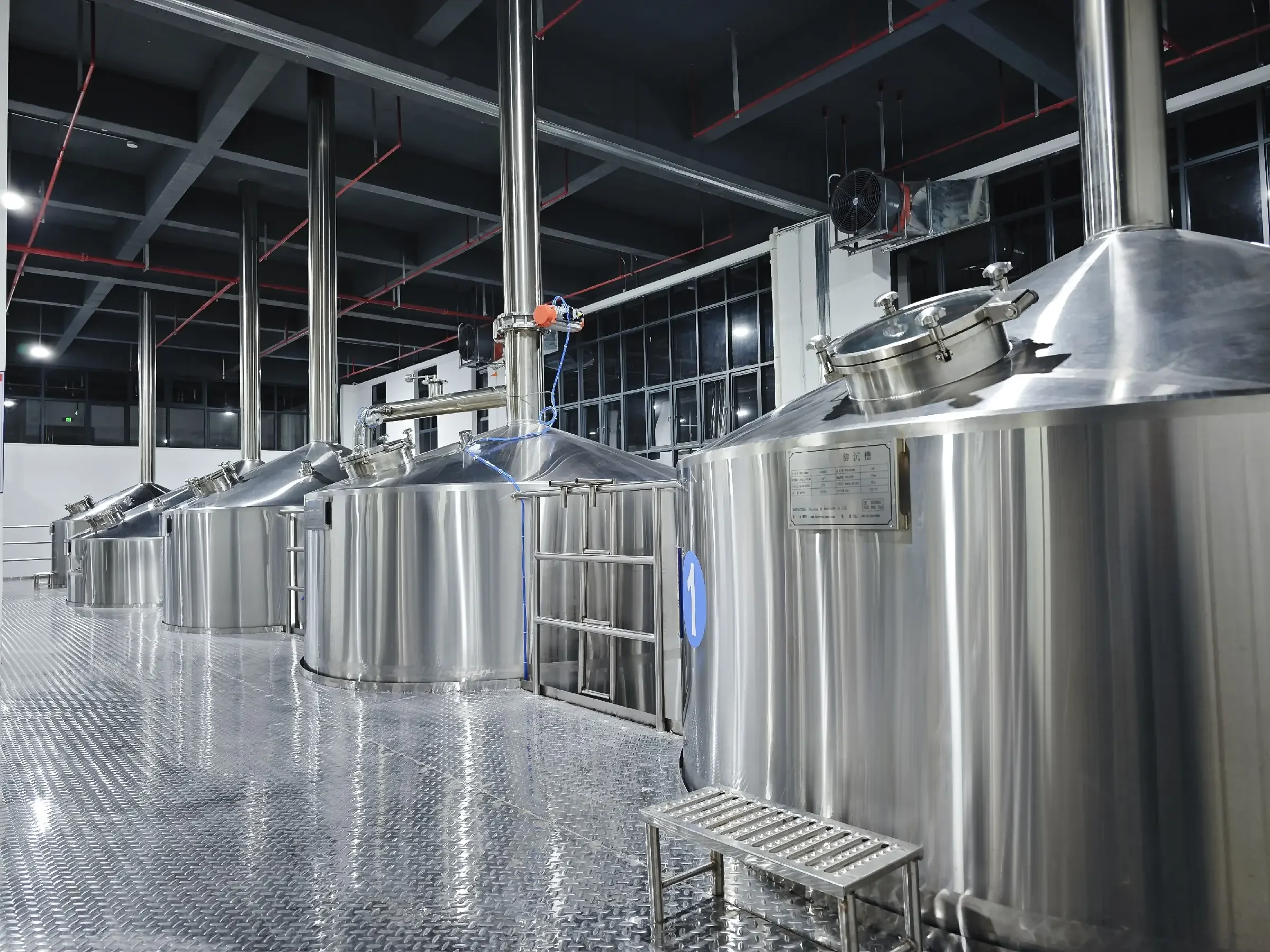 贵阳某酿酒设备展厅内的小型不锈钢酿酒设备实拍，包含蒸锅、冷却器及连接管道。_1