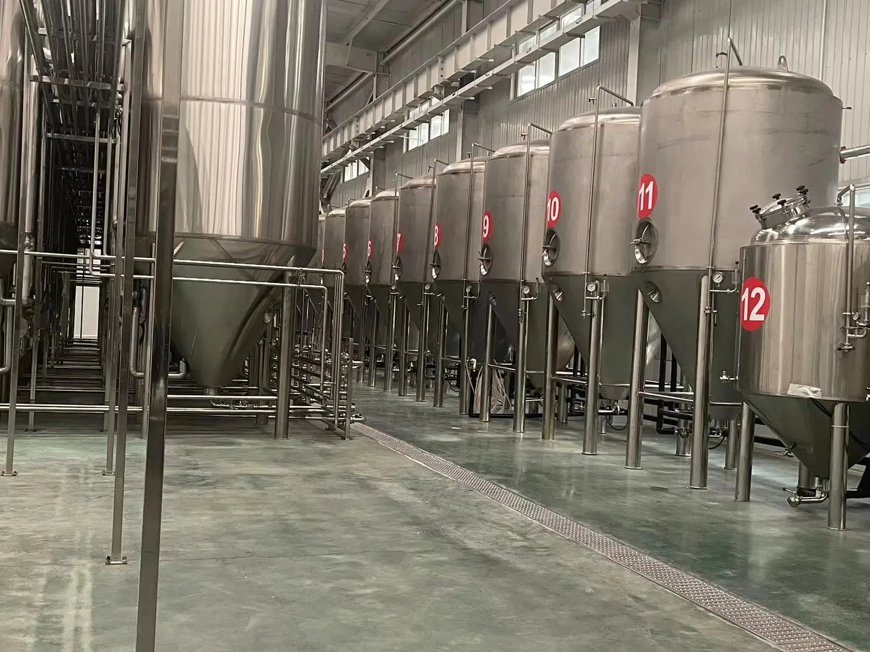 德州啤酒设备厂家车间内，老师傅正在仔细检查和调试一台崭新的不锈钢小型精酿啤酒酿造设备_1