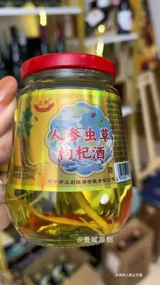 家庭自制人参虫草枸杞酒：透明玻璃罐内盛满金黄色酒液，清晰可见浸泡的完整人参、虫草和红枸杞。_1