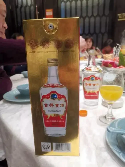 南楼山酿酒技术网酿酒车间实景：酿酒师傅正在检查陶坛中的粮食酒醅，背景是成堆的酿酒原料和储藏的酒坛_1