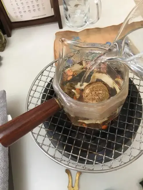家庭自制花旗参酒的特写照片，展示玻璃酒坛、花旗参和枸杞在酒液中的状态_1