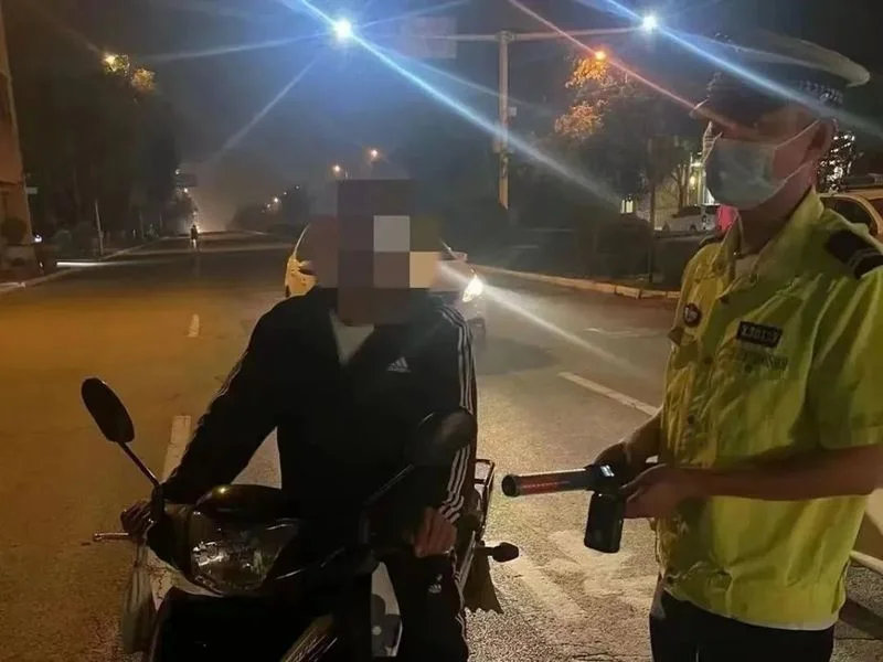 交警夜间对摩托车驾驶员进行酒精测试，警示酒驾行为。_1