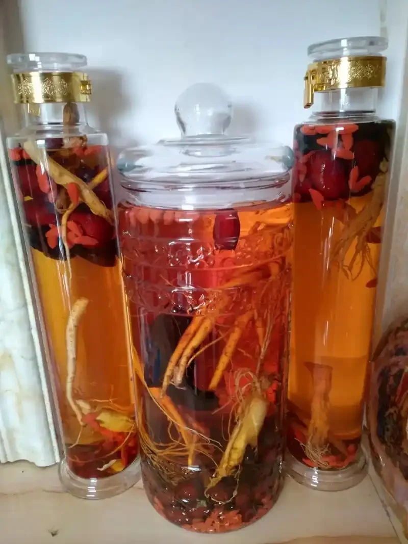 老年人养生泡酒材料展示：玻璃罐中泡着红枣、枸杞、人参，旁边散落着未浸泡的原材料。_1