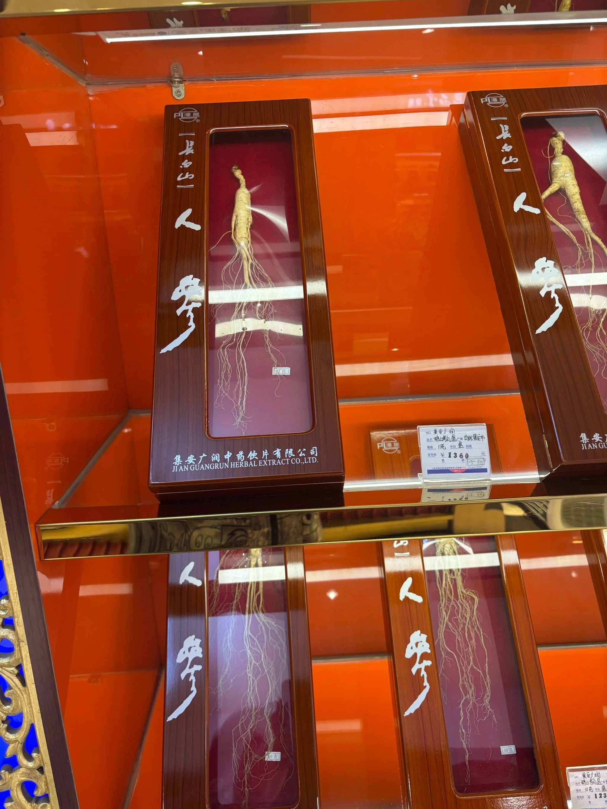 玻璃酒坛中人参和西洋参切片与整根浸泡在琥珀色酒液中的特写，旁边摆放着枸杞、冰糖及传统药秤，展示家庭泡制药酒的专业场景_1