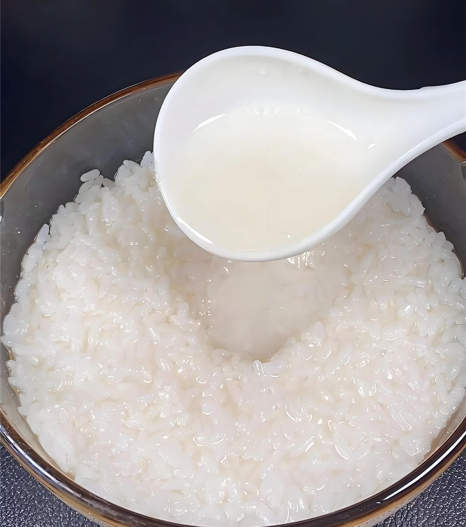 家庭自制成功的甜酒酿特写：洁白糯米浸泡在清亮酒汁中，中间酒窝蓄满汁液，展现出色泽诱人、制作成功的状态。_1