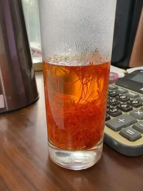 玛咖藏红花泡酒成品展示：玻璃罐中浸泡着玛咖片和藏红花，酒液呈琥珀色，旁边有枸杞和当归点缀_1